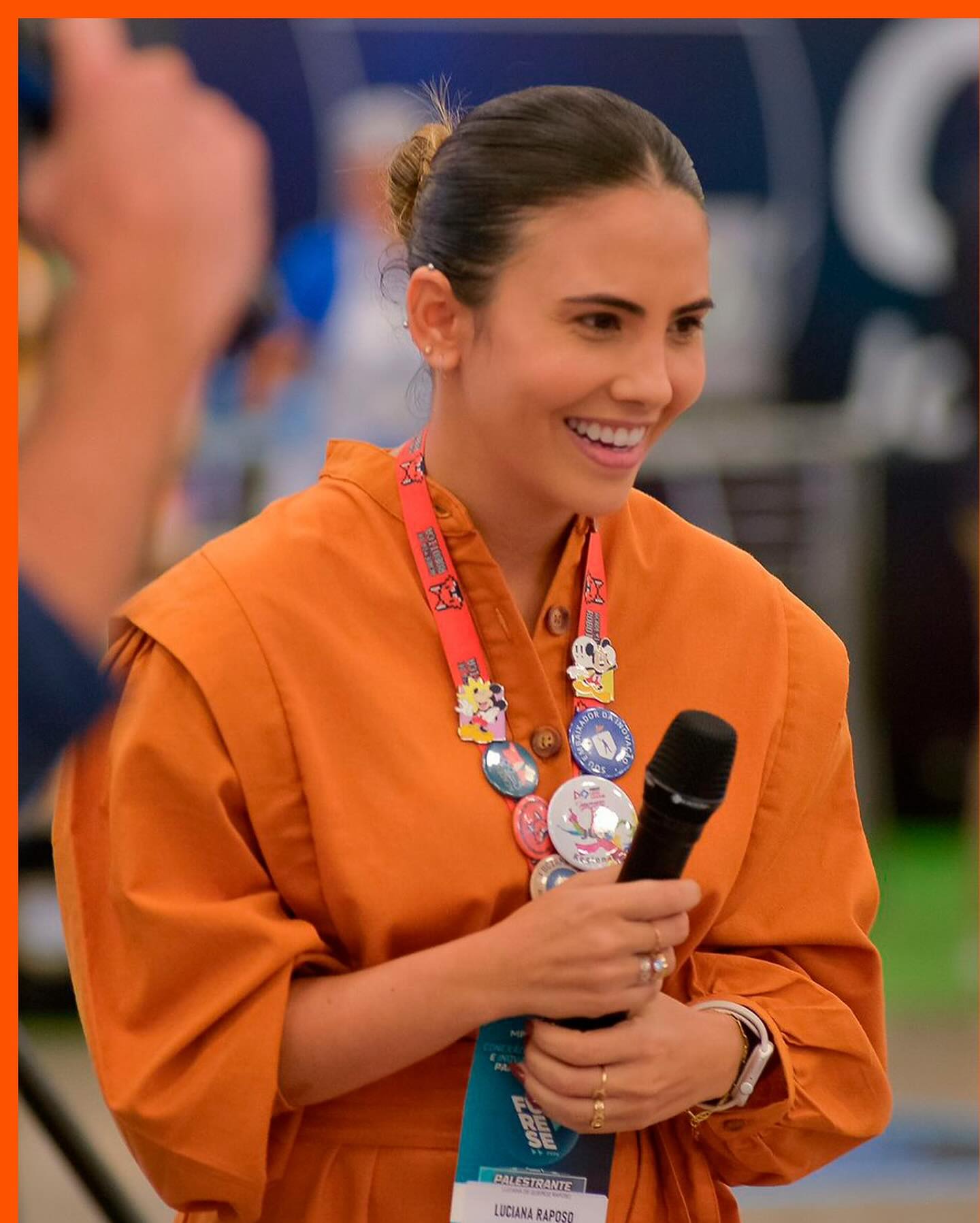 Luciana Raposo, Diretora/CEO da Academia de Robótica, sorrindo com um microfone na mão durante um evento
